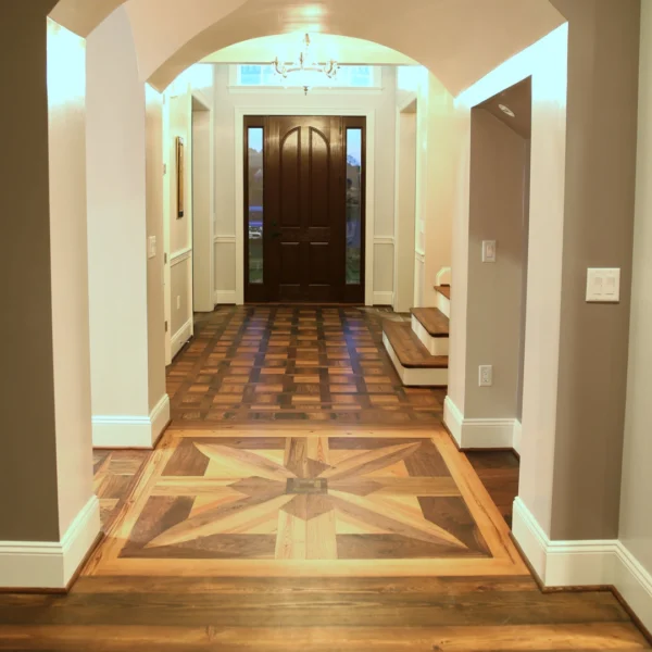 A beautifully designed hallway featuring a star pattern in the wooden floor and an entrance door.